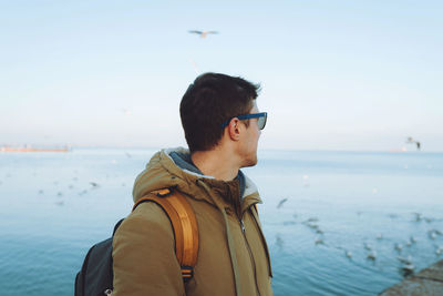 Young cheerful man walking by the sea in winter time. travel and active lifestyle concept person