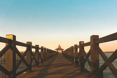 Footbridge over pier against clear sky