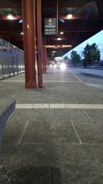 Empty road by illuminated buildings in city at night