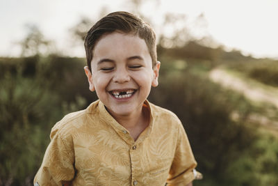 Portrait of school-aged boy missing two front teeth with eyes closed