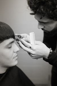 Barber cutting hair of man at salon