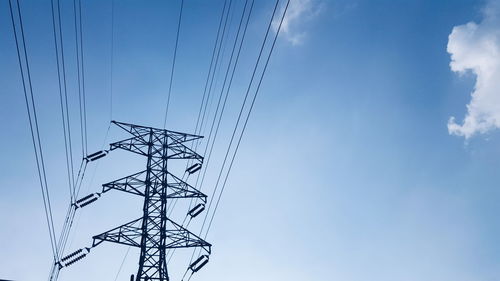 Low angle view of electricity pylon against cloudy sky