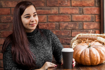 Woman having coffee by pumpkin in cafe