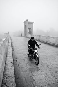 Rear view of man riding motorcycle on road against clear sky