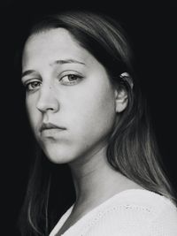 Portrait of young woman against black background