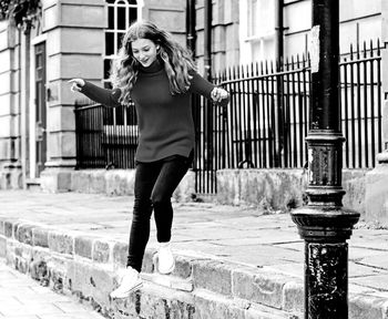 Young woman standing against wall in city