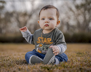 Portrait of cute boy sitting on field