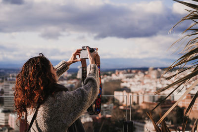 Woman photographing with cityscape in background