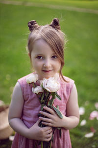 Portrait of a beautiful baby girl in a pink dress standing with a bouquet of flowers