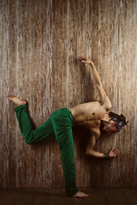 Full length of young man dancing against wall