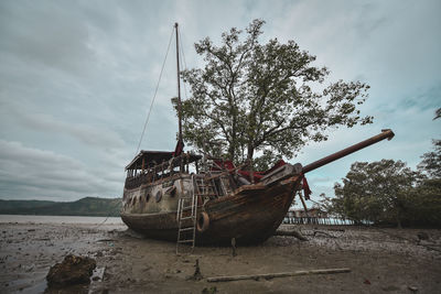 Boat moored on beach against sky