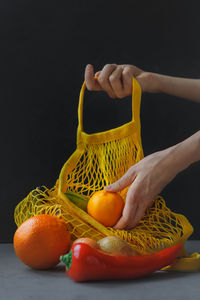 Close-up of hand holding fruits against black background