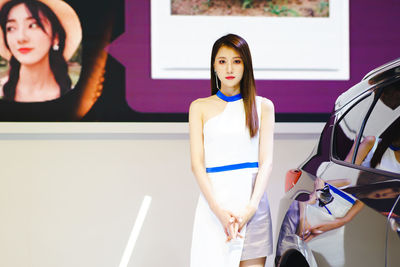 Portrait of young woman standing against wall