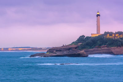 Lighthouse by sea against sky