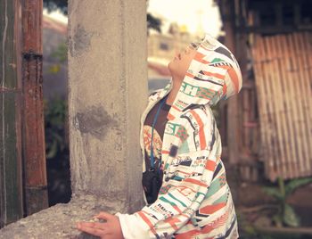 Boy in hooded shirt looking up by pole