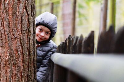 Portrait of cute boy in tree trunk during winter
