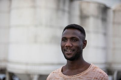 Young man looking away while standing outdoors