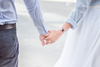 Midsection of couple holding hands