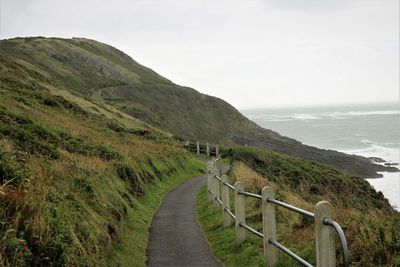 Scenic view of road by sea against clear sky