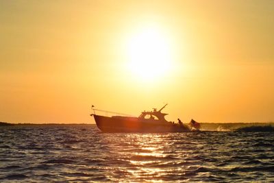 Boat sailing in sea against sky during sunset