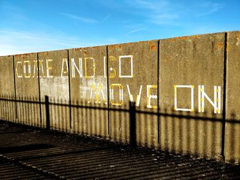 Text on wall against blue sky