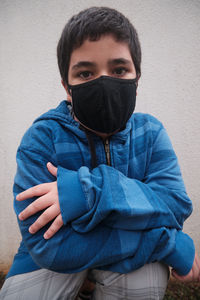 Portrait of teenage boy covering face against wall