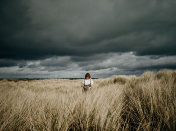 Rear view of woman standing on field against sky