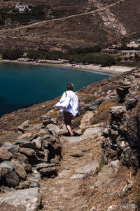 Rear view of woman walking on mountain trail leading towards sea