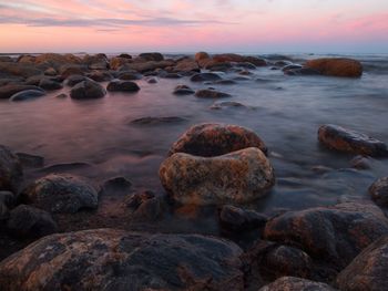 Rocks at sea shore during sunset