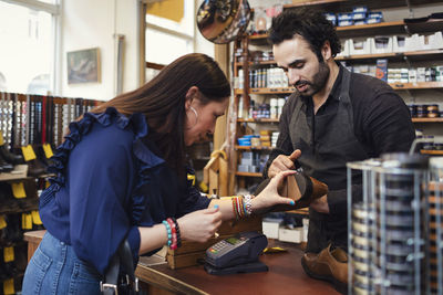 Shoemaker showing shoe to female customer in store