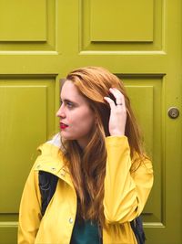 Beautiful woman with hand in hair standing against door