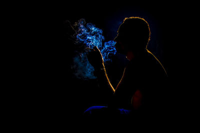Man smoking cigarette against black background
