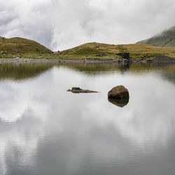 Scenic view of lake by mountain against sky