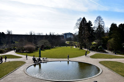 People in park by lake against sky