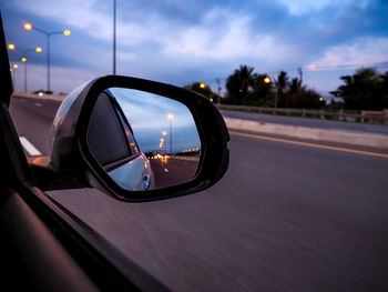 Reflection of highway on car side-view mirror at dusk
