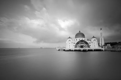 View of building by sea against cloudy sky