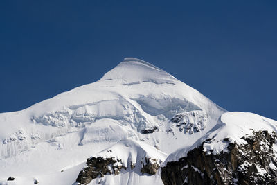 Scenic view of snowcapped mountains against clear blue sky