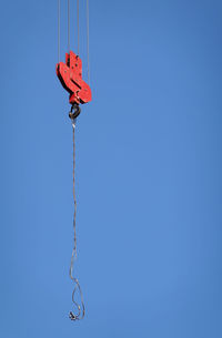Low angle view of kite hanging against clear blue sky