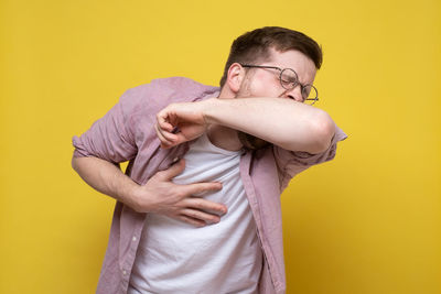 Full length of young man standing against yellow background