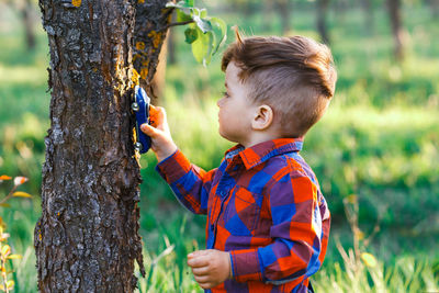 Side view of boy on tree trunk