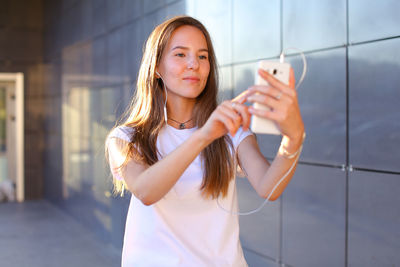 Portrait of young woman standing against wall