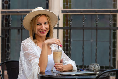 Portrait of smiling woman with coffee sitting at outdoor cafe