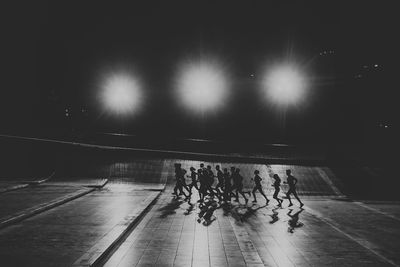 Group of people walking on illuminated floor at night