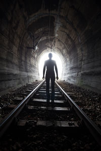 Rear view of silhouette man walking in tunnel
