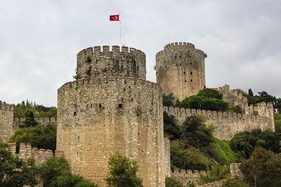 Low angle view of historic stone 15th century rumelian castle with turkish flag,  istanbul, turkey