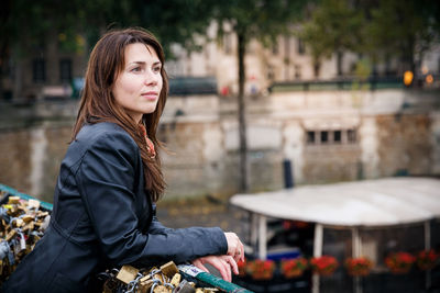 Brunette girl in a black jacket stands on the bridge