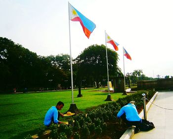 People on grassy field against cloudy sky