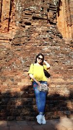 Portrait of woman standing against stone wall