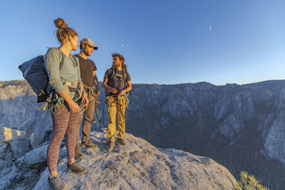 Three hikers at the top of el capitan in yosemite valley at sunset