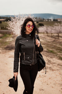 Portrait of smiling young woman wearing sunglasses standing on land